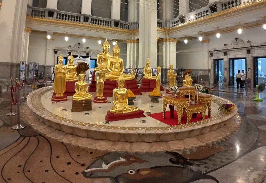 หลวงพ่อโสธร พระพุทธรูปสีทองหลายองค์บนแท่นกลม ภายในอาคารขนาดใหญ่