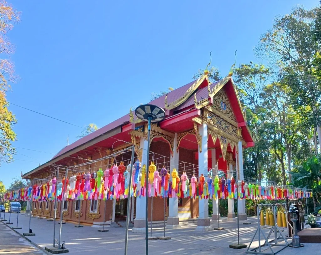 พระอุโบสถวัดจุฬาภรณ์วนาราม จังหวัดนครนายก ตกแต่งลวดลายสีทอง และประดับโคมล้านนาหลากสีบริเวณลานด้านหน้า