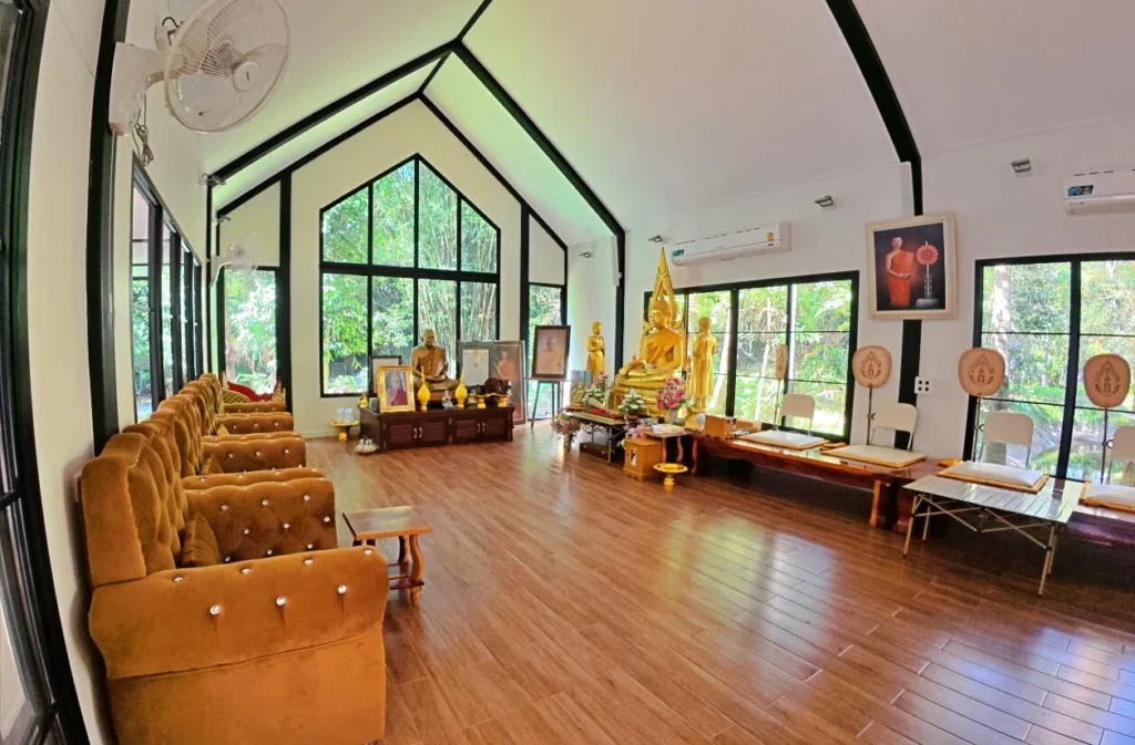 ภายในอาคารปฏิบัติธรรมวัดจุฬาภรณ์วนาราม บรรยากาศร่มรื่น รายล้อมด้วยต้นไม้และพื้นที่ธรรมชาติ
