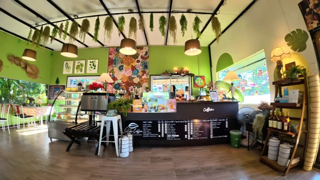 บรรยากาศภายในคาเฟ่เอเดนฟาร์ม นครนายก ตกแต่งโทนสีเขียวสดใส พร้อมเคาน์เตอร์เครื่องดื่มและเมนูกาแฟ