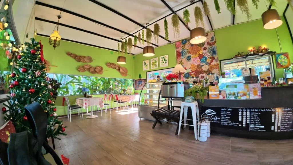 บรรยากาศภายในคาเฟ่เอเดนฟาร์ม นครนายก ตกแต่งโทนสีเขียวสดใส พร้อมเคาน์เตอร์เครื่องดื่มและเมนูกาแฟ