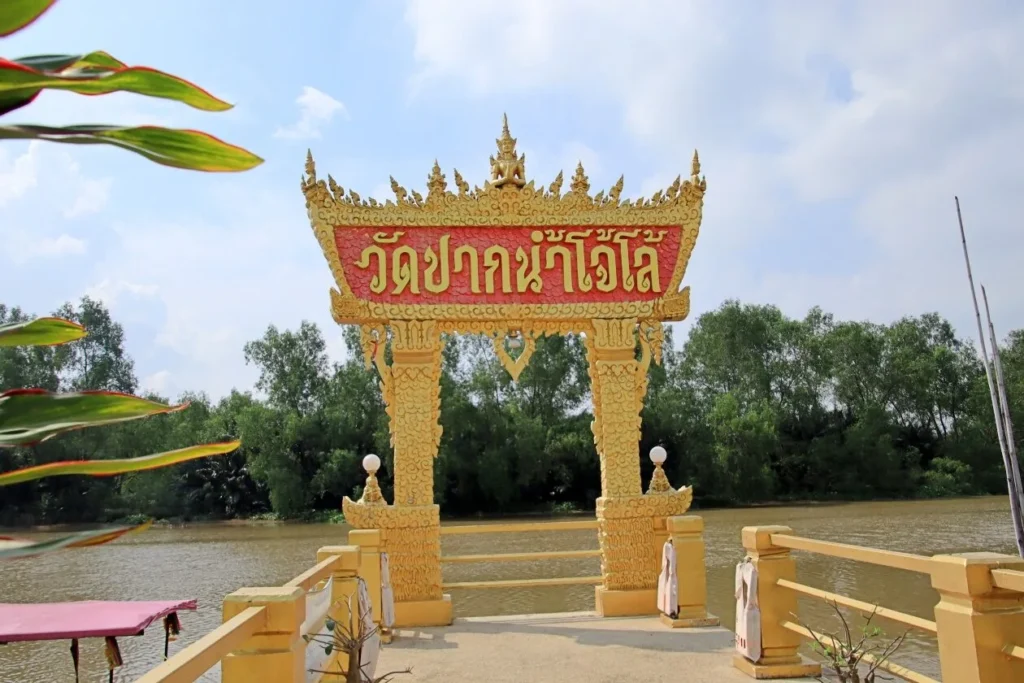 ซุ้มประตูวัดสีทองริมแม่น้ำ มีป้ายชื่อวัดภาษาไทย พร้อมวิวต้นไม้และสายน้ำด้านหลัง