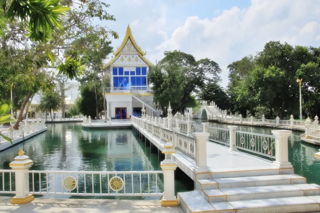 อาคารวัดสีขาวริมสระน้ำ มีสะพานเชื่อมและต้นไม้ร่มรื่น บรรยากาศสงบ