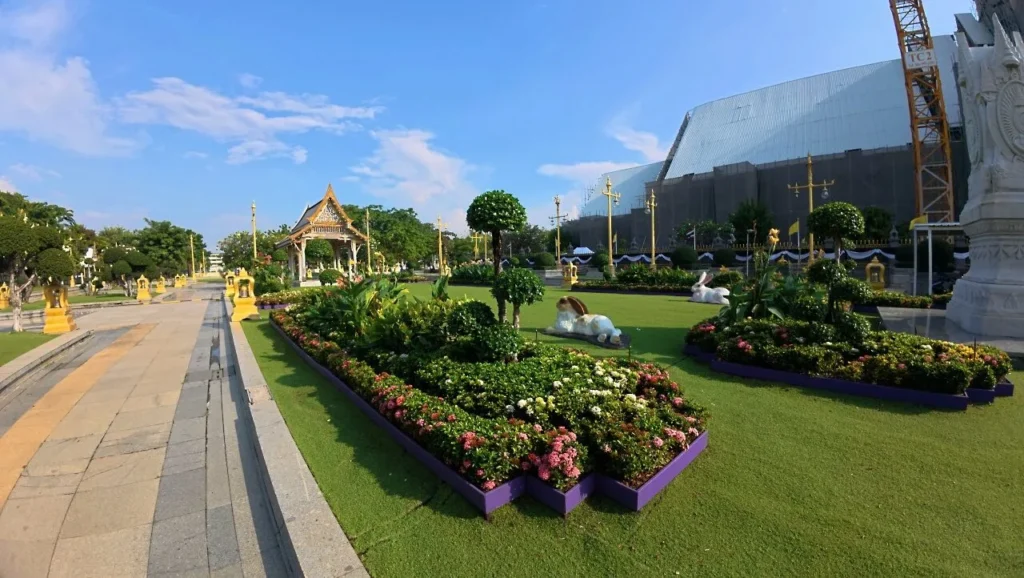 สวนหย่อมภายในวัด ตกแต่งไม้ดอกและรูปปั้นสัตว์ มีศาลาและอาคารด้านหลัง