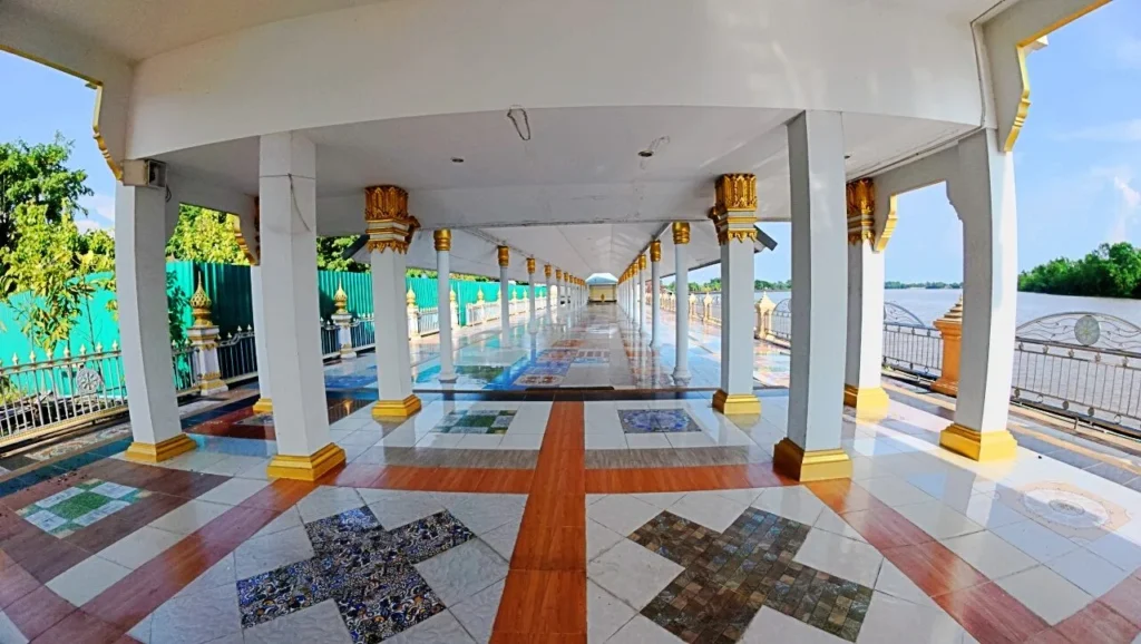 ทางเดินริมแม่น้ำในวัด มีเสาเรียงยาวและพื้นลวดลายกระเบื้อง