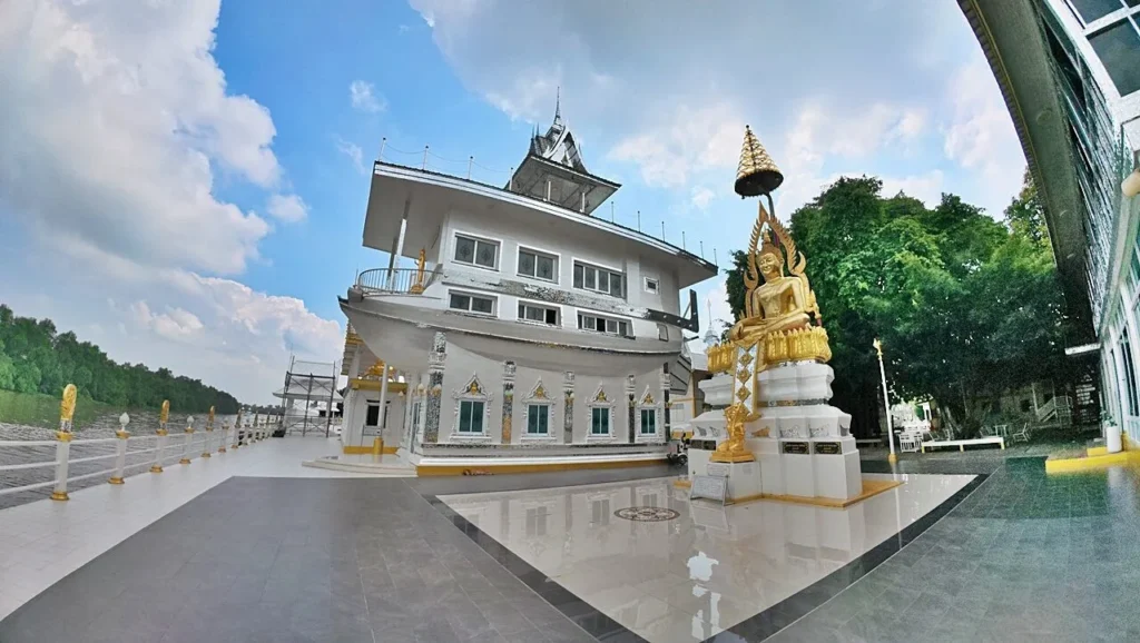 วิหารสีขาวตกแต่งลวดลายไทยประดับกระจก ตั้งอยู่กลางสระน้ำสีเขียว พร้อมสะพานและต้นไม้โดยรอบ